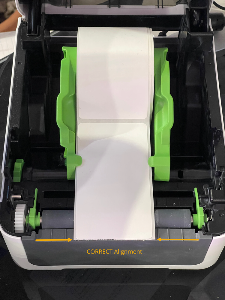 Brother TD-4550DNWB label printer with the roll compartment cover open and the correct label alignment highlighted.